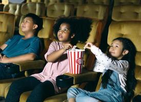 grupo de niños de diversidad afroamericanos y asiáticos viendo películas juntos en el teatro. foto