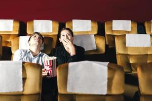 Caucasian man and woman watching a movie in theater. photo