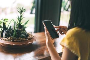 Close up of adult female hand using mobile phone for digital application online at cafe. photo