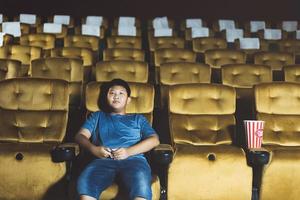 Alone asian boy go to cinema with bored feel. photo