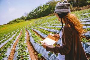 Asian woman travel nature. Travel relax. Girl reading a book In the vegetable garden. Nature Education Write a note in the garden Strawberry. Thailand photo