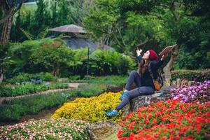 woman travel nature in the flower garden. relax sitting on rocks and reading books In the midst of nature at national park doi Inthanon. photo