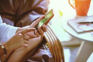 Woman hand is playing mobile phone. Sit on the sofa. photo