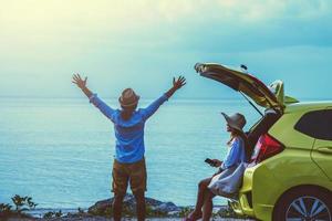 Asian lover couple woman and man travel nature. Travel relax. Sitting on the car at the beach. In the summer photo