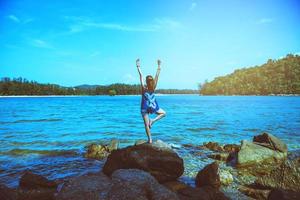 las mujeres asiáticas se relajan en las vacaciones. viajar relajarse. jugar si yoga. sobre las rocas junto al mar. en el verano. tailandia foto