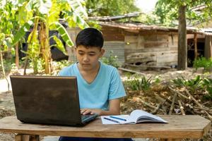 un niño está estudiando en línea con una computadora portátil en su escritorio en casa en el campo foto