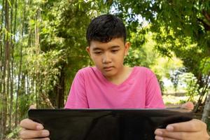 la cara del niño está estudiando en línea con una computadora portátil en casa en el campo foto