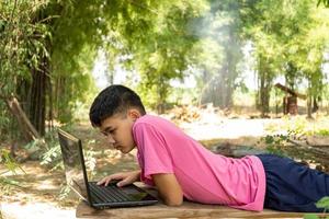 un niño está estudiando en línea con una computadora portátil en medio de la naturaleza en casa en el campo foto