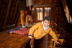 niño con ropa de otoño acostado en una mesa grande y jugando foto