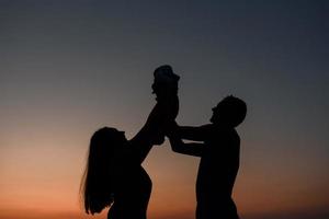 los padres jóvenes caminan con su pequeño hijo en el campo foto