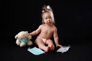 a small child sits next to a sick teddy bear. the concept photo