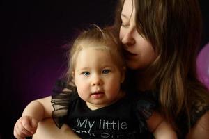 first year baby girl's birthday party day. ballons and holiday indoors. child's birthday. little pretty girl with her mother in black dress photo