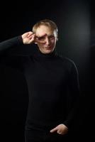 Portrait of determined goodlooking man wearing black shirt, black background. photo