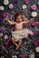 Portrait of a sweet little baby girl with a wreath of flowers on her head indoors photo