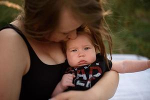 joven madre abrazando lindo bebé al aire libre foto