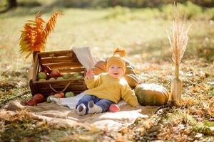 Cute little girl sitting on pumpkin and playing in autumn forest photo