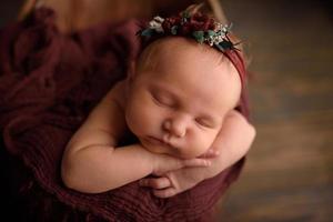 Cute newborn girl sleeping in a tub on a wooden background. photo