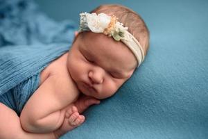 Cute newborn girl sleeping on a blue background in a blue wrapping. photo