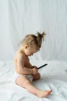 Cute little baby is talking on cell phone, isolated over white photo