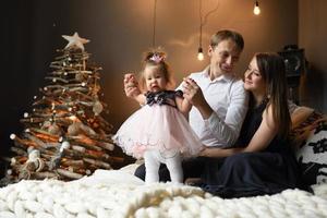 Father mom and their little one year old daughter have fun together before christmas. photo