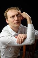 Close up portrait of a young man in a white shirt and black tie, smiling while looking at the camera, against plain studio background photo