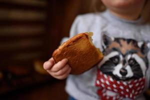 Little girl in the kitchen eats sweet pastries. photo