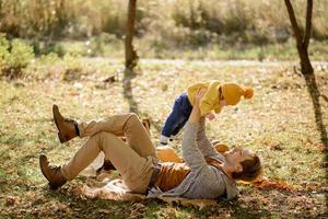 feliz padre e hija en el parque de otoño sobre hojas amarillas foto