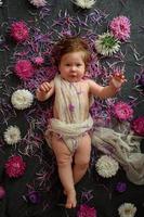 Portrait of a sweet little baby girl with a wreath of flowers on her head indoors photo