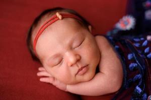 Newborn girl sleeping on a red cloth in a red wrapper photo