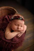 Cute newborn girl sleeping in a tub on a wooden background. photo