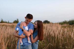 Young parents walk with their little son in the field photo