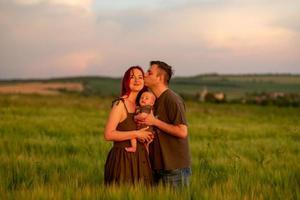 Father, mother and their little son have fun together in a wheat field. photo