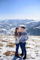 Loving couple playing together in snow outdoor. Winter holidays in mountains. Man and woman wearing knitted clothing having fun on weekends. photo