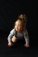 little girl sitting on a black background photo