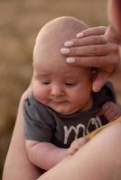 una madre sostiene con ternura a su hijo de tres meses en sus brazos en un campo de trigo. foto