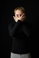 Portrait of determined goodlooking man wearing black shirt, black background. photo