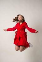 gente, movimiento, felicidad y concepto de vacaciones - mujer joven feliz con vestido rojo saltando alto en el aire foto