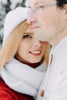 Young man with bag hugs his girlfriend in winter forest photo