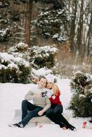 Happy couple in winter drinking tea and sitting on a sled photo