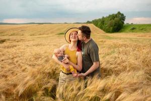 Father, mother and their little son have fun together in a wheat field. photo