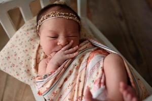 Newborn girl lying on a miniature crib photo