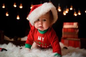 Una niña de 7 meses con un traje rojo de Navidad sobre un fondo de guirnaldas retro se sienta en una piel foto
