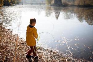niño pequeño en el parque de otoño pruhonice república checa alimentando patos y peces, trepando árboles, andando en bicicleta, caminando foto