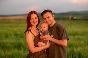 padre, madre y su pequeño hijo se divierten juntos en un campo de trigo. foto