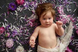 Portrait of a sweet little baby girl with a wreath of flowers on her head indoors photo