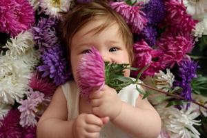 niña en vestido azul jugando con ramo de tulipanes rosas. niño pequeño en casa en la guardería soleada. niño divirtiéndose con flores foto