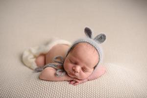 Newborn baby boy in a knitted hat sleeps on a light knitted blanket. photo