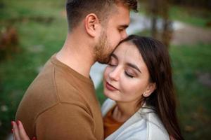 Young couple in love holding hands and walking through a park on a sunny autumn day photo