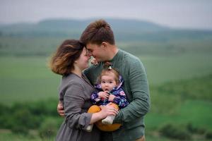 mamá, papá e hija. los padres sostienen al bebé con las manos y van hacia la cámara. foto