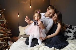 Father mom and their little one year old daughter have fun together before christmas. photo